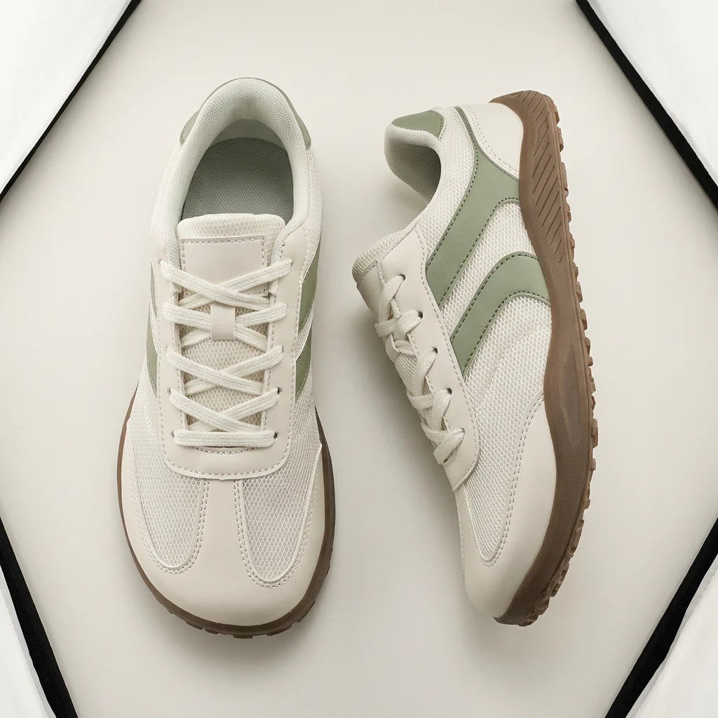 Pair of light-colored sneakers with brown soles on a white background