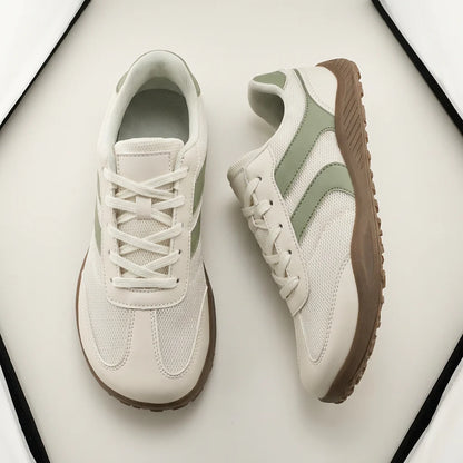 Pair of light-colored sneakers with brown soles on a white background