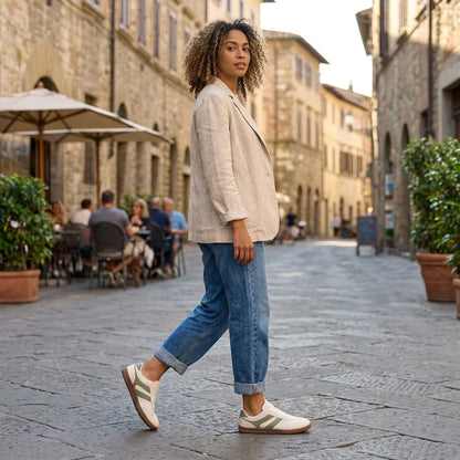 Woman walking on a street in an Italian town with stone buildings and outdoor seating.