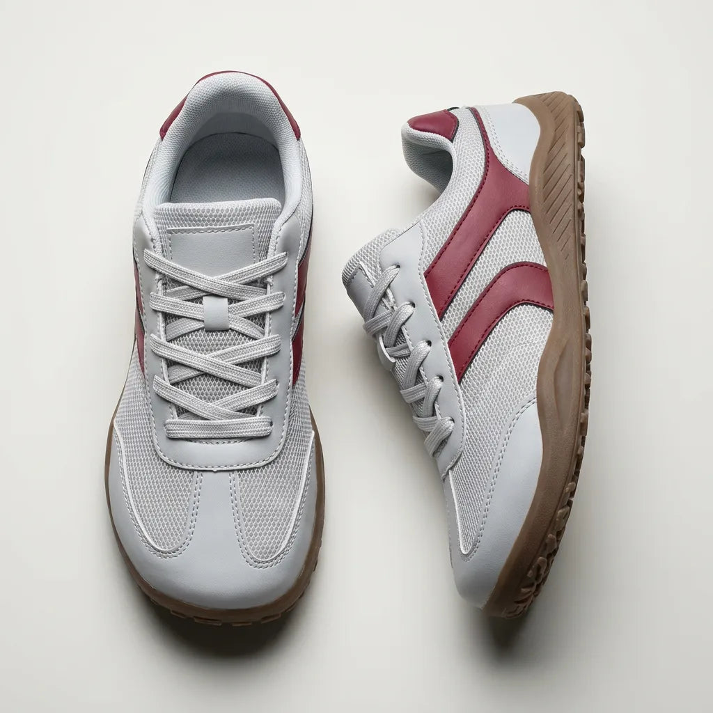 Pair of gray sneakers with red accents on a light gray background