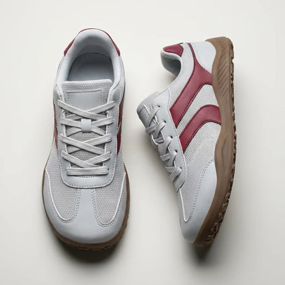 Pair of gray sneakers with red accents on a light gray background