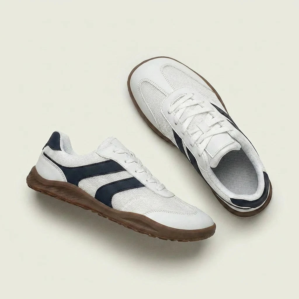 White sneakers with navy accents and brown soles on a light beige background